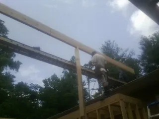 Carpenter setting a ridge beam over a new addition frame — Ice Dam Removal by Roofing Brothers in Amagansett