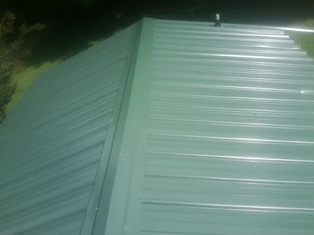 New green metal panels meeting at the ridge of a roof — Flat Roof Repair work by our crew in Amagansett