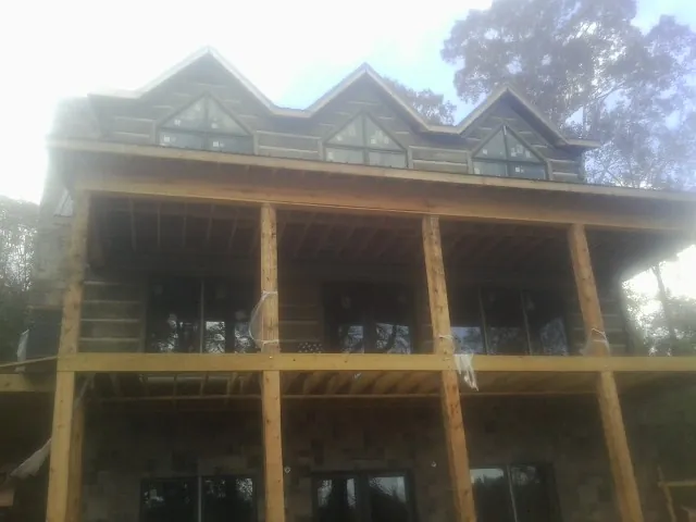 Dormers and porch framing on a large log home under construction — Roof Coating work by our crew in Amagansett
