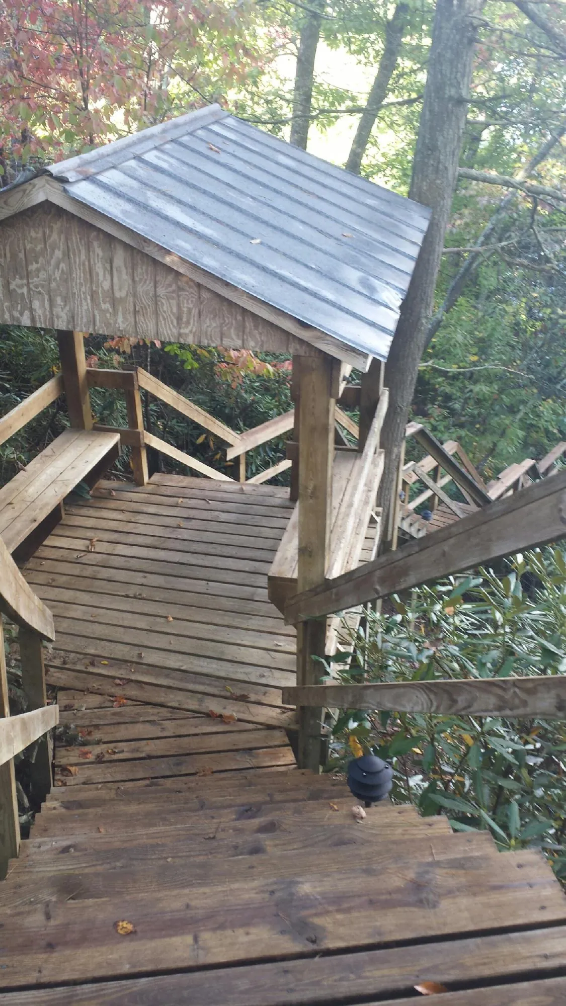 Metal roofed shelter over wooden steps on a wooded walkway — Skylight Repair & Installation work by our crew in Amagansett