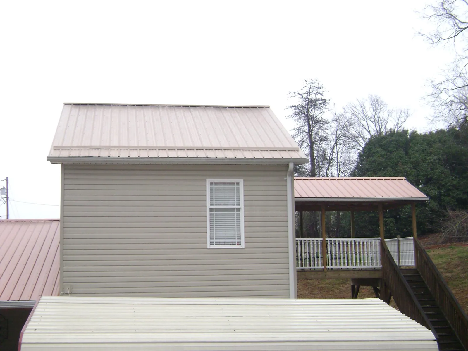 Tan metal roofs on a two story addition and attached porch, from a Roof Replacement job in Amagansett