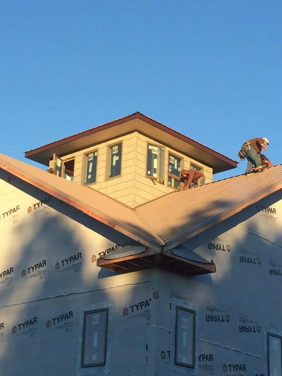 Roofers working around a rooftop cupola on a new metal roof at sunset — Roof Waterproofing in Amagansett by Roofing Brothers